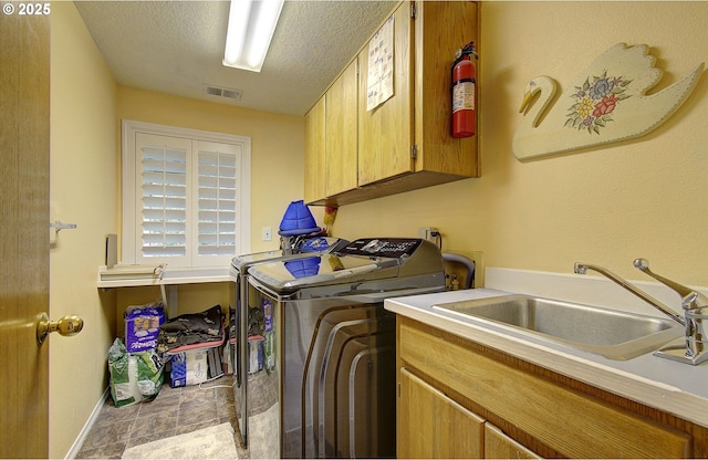 10535 SW 135th Ave, Beaverton, OR 97008 - washroom featuring cabinet space, washer and clothes dryer, a textured ceiling, and stone finish floors