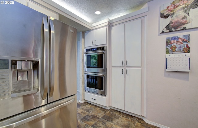 10535 SW 135th Ave, Beaverton, OR 97008 - kitchen featuring stainless steel appliances, a textured ceiling, stone finish floors, white cabinetry, and recessed lighting