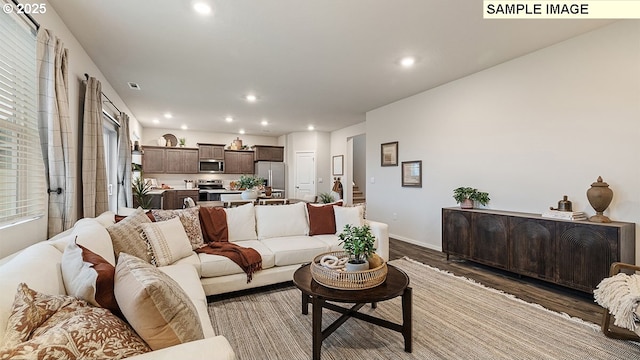 living room featuring recessed lighting, baseboards, wood finished floors, and stairs