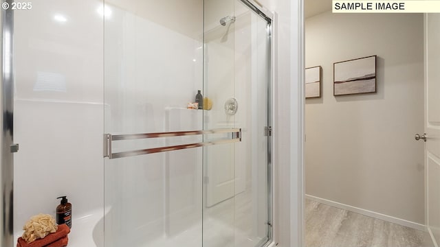 full bathroom featuring wood finished floors, a stall shower, and baseboards