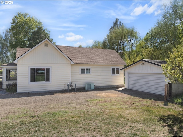 rear view of property featuring central air condition unit, an outdoor structure, roof with shingles, and a lawn