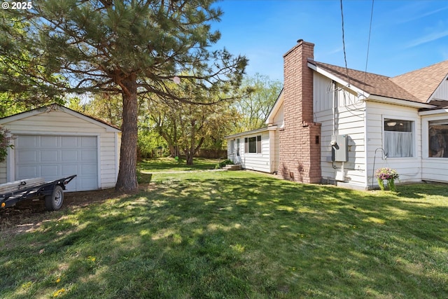 view of green lawn featuring a detached garage and an outdoor structure