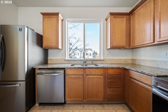 kitchen with stainless steel appliances, light stone countertops, and sink