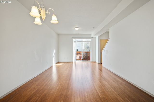 unfurnished living room with an inviting chandelier and light wood-type flooring