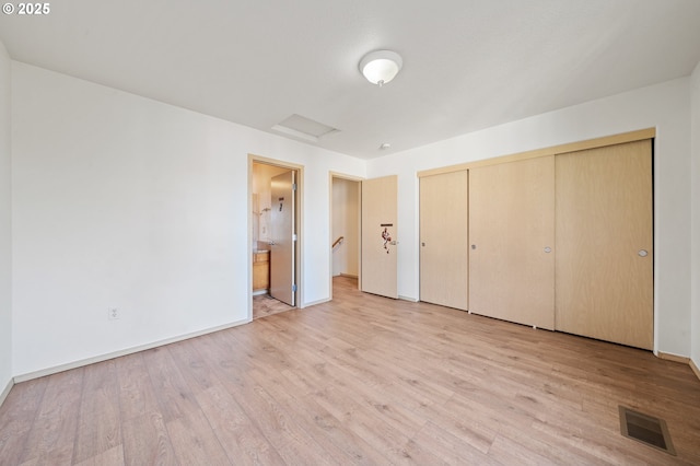 unfurnished bedroom featuring connected bathroom, light hardwood / wood-style floors, and a closet