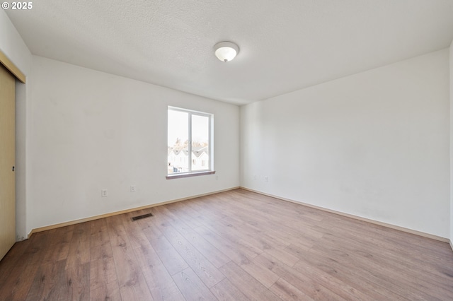 spare room featuring light hardwood / wood-style flooring and a textured ceiling