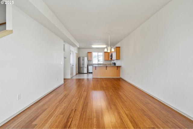 unfurnished living room with a chandelier and light wood-type flooring