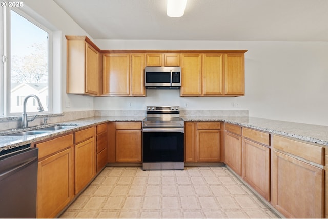 kitchen featuring stainless steel appliances, sink, and light stone counters