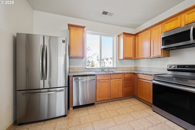 kitchen featuring sink, light stone countertops, and appliances with stainless steel finishes