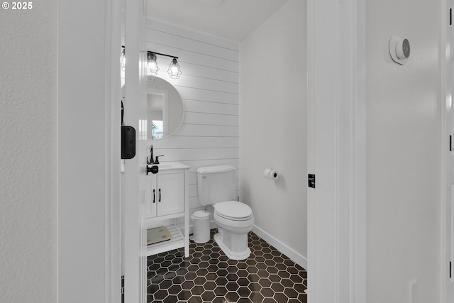 bathroom with toilet, vanity, tile patterned floors, and wood walls