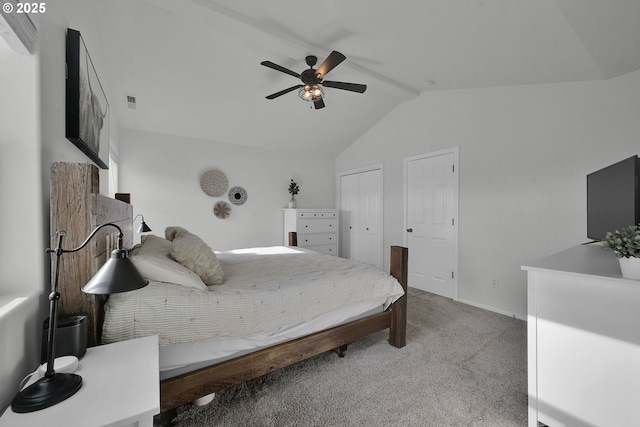 bedroom with lofted ceiling, light colored carpet, ceiling fan, and two closets