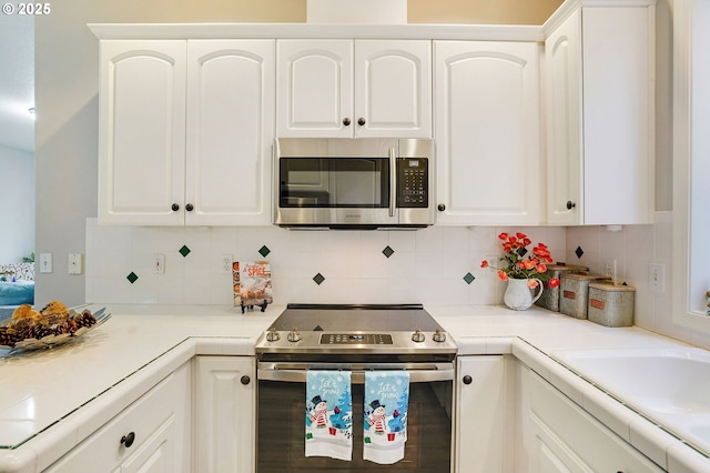 kitchen with white cabinets, appliances with stainless steel finishes, and decorative backsplash