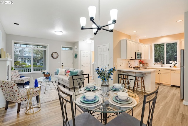 dining area with light hardwood / wood-style floors, sink, and a chandelier