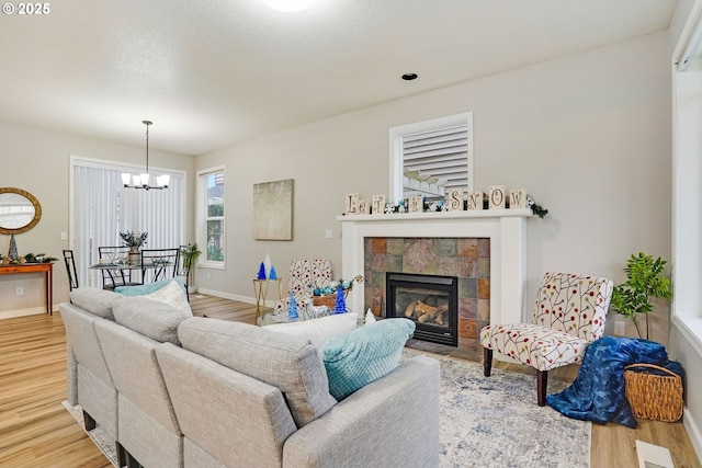 living room with hardwood / wood-style flooring, a notable chandelier, and a tiled fireplace