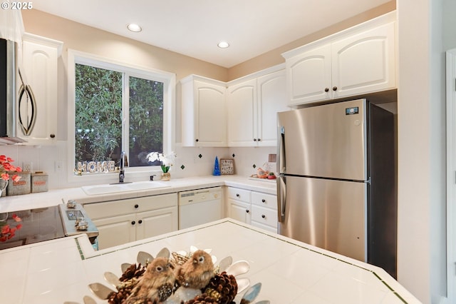 kitchen featuring white cabinetry, sink, stainless steel appliances, and tile counters