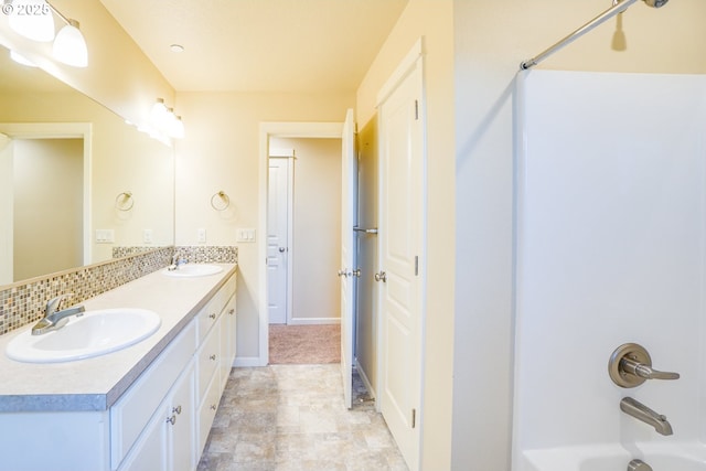 full bathroom with  shower combination, double vanity, baseboards, and a sink