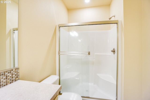 bathroom featuring a stall shower, vanity, toilet, and decorative backsplash