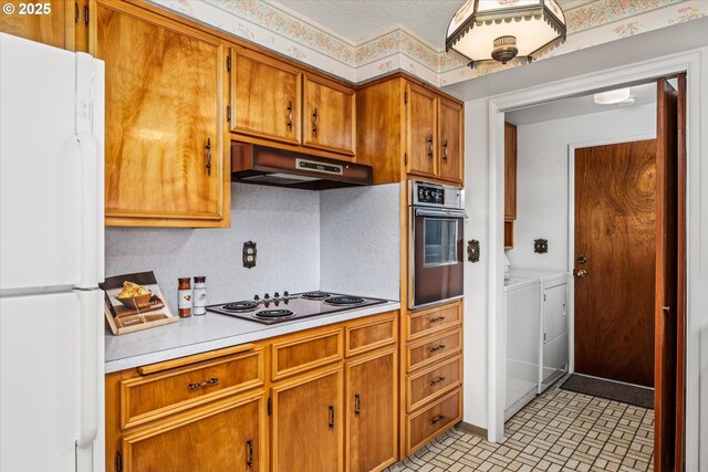 82091 Lost Valley Ln, Dexter, OR 97431 - kitchen with freestanding refrigerator, oven, under cabinet range hood, washing machine and clothes dryer, and black electric cooktop