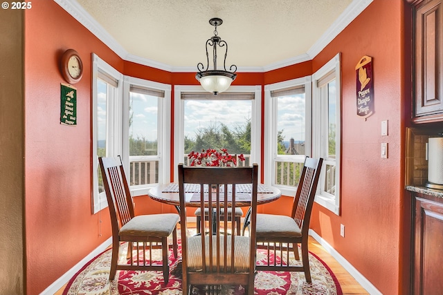 dining room with crown molding, baseboards, a textured wall, and light wood-style flooring