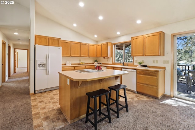 kitchen featuring white appliances, a kitchen island, a breakfast bar area, light countertops, and a sink