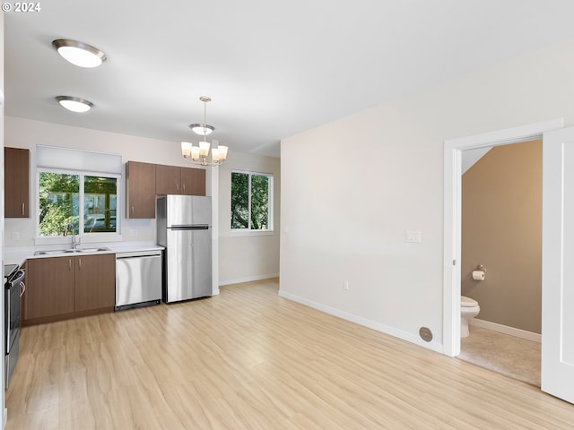 kitchen with stainless steel appliances, decorative light fixtures, sink, and a wealth of natural light