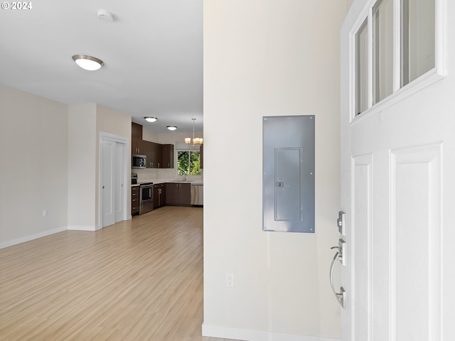 foyer with sink, electric panel, a chandelier, and light hardwood / wood-style flooring