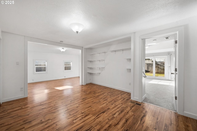 interior space with baseboards, visible vents, a textured ceiling, and wood finished floors