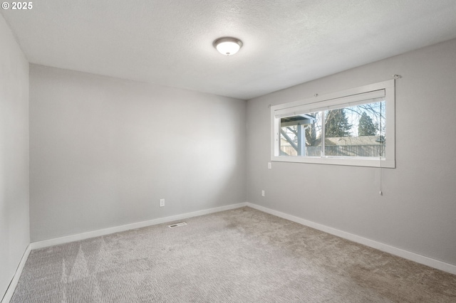 carpeted empty room featuring visible vents, baseboards, and a textured ceiling