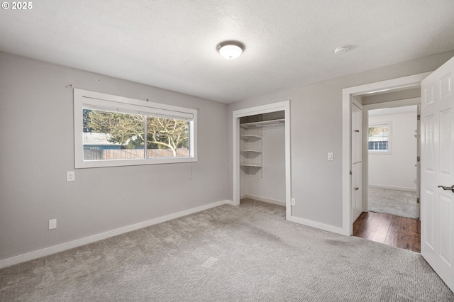 unfurnished bedroom with baseboards, multiple windows, a textured ceiling, and carpet flooring