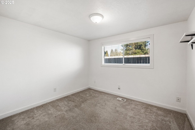 carpeted spare room featuring visible vents and baseboards