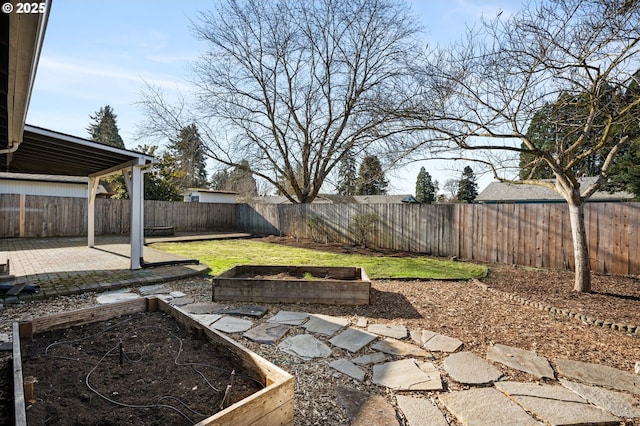 view of yard featuring a patio, a fenced backyard, and a garden