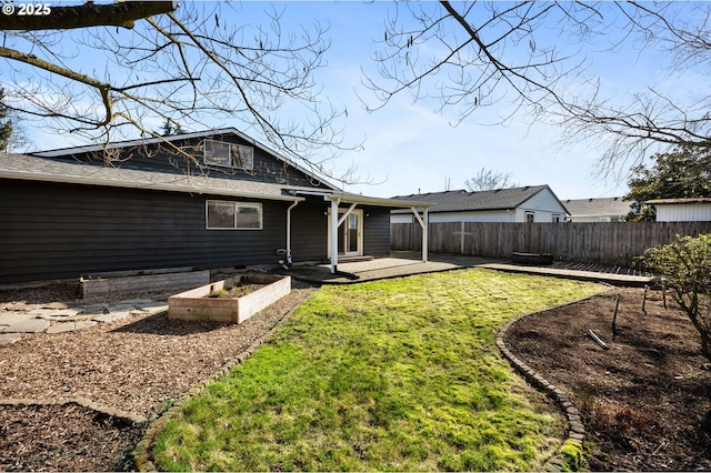 back of house featuring a yard, a vegetable garden, and fence