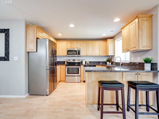 1091 56th St, Washougal, WA 98671 - kitchen with appliances with stainless steel finishes, light brown cabinets, a peninsula, a sink, and light wood-style flooring
