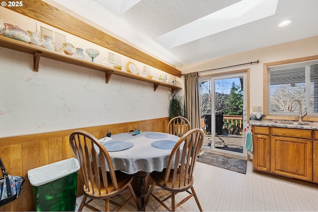 dining area with recessed lighting, a textured ceiling, wood walls, and a wainscoted wall