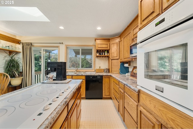 kitchen with open shelves, white appliances, recessed lighting, light stone counters, and a skylight