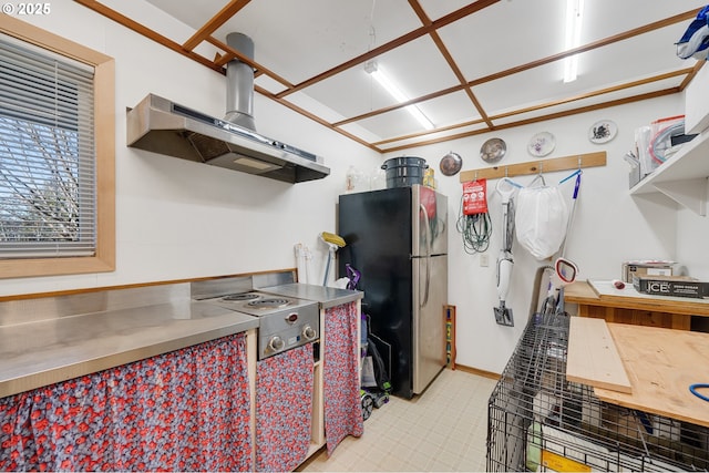 kitchen featuring freestanding refrigerator, cooktop, stainless steel counters, and exhaust hood