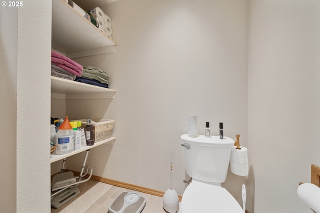 bathroom featuring baseboards, tile patterned floors, and toilet