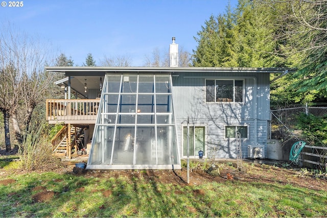 back of property with a chimney, a wooden deck, a sunroom, fence, and stairs