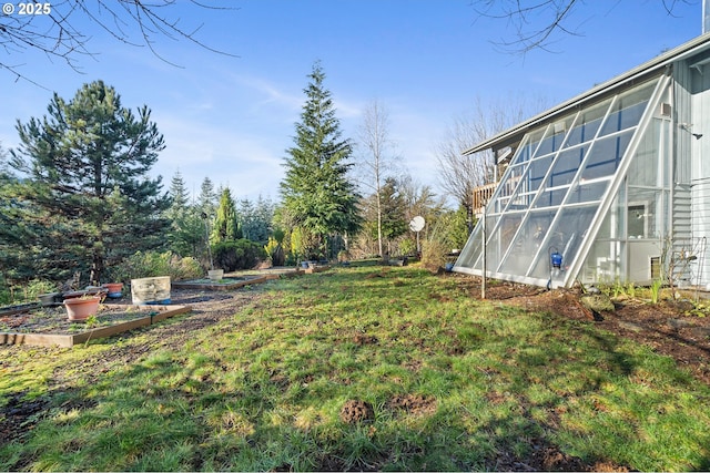 view of yard featuring a greenhouse and a vegetable garden