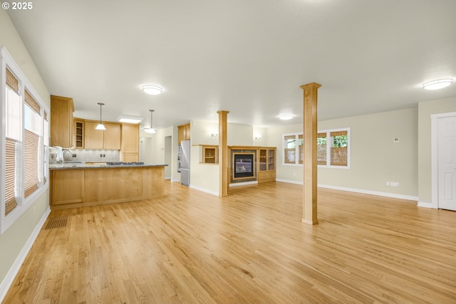 7307 SW Capitol Hwy, Portland, OR 97219 - unfurnished living room with a glass covered fireplace, light wood-style flooring, and decorative columns