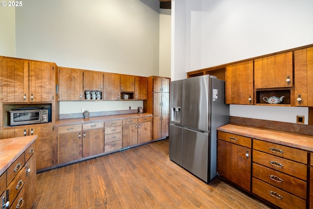 kitchen featuring stainless steel refrigerator with ice dispenser, a towering ceiling, and hardwood / wood-style floors