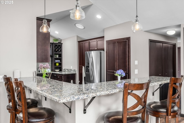 870 Sheraton Dr, Eugene, OR 97401 - kitchen with stainless steel fridge, dark brown cabinets, hanging light fixtures, lofted ceiling, and light stone countertops