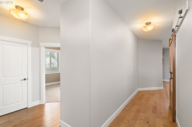 corridor with a barn door and light hardwood / wood-style flooring