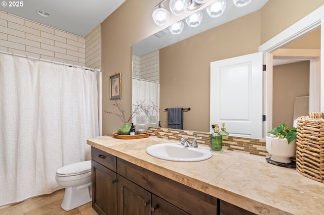 bathroom with decorative backsplash, vanity, and toilet