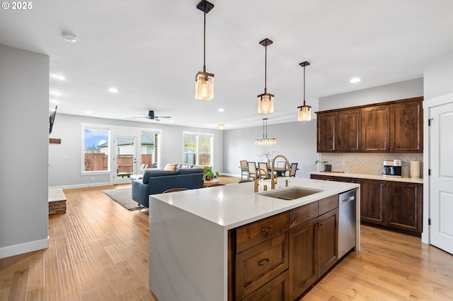 kitchen with a kitchen island with sink, sink, stainless steel dishwasher, ceiling fan, and decorative light fixtures