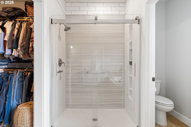 bathroom featuring toilet and a shower with shower door