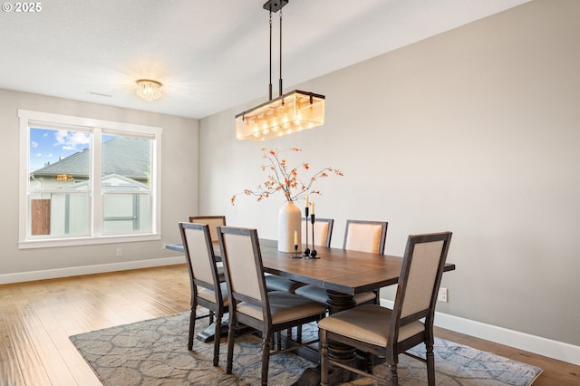 dining area with hardwood / wood-style flooring and an inviting chandelier