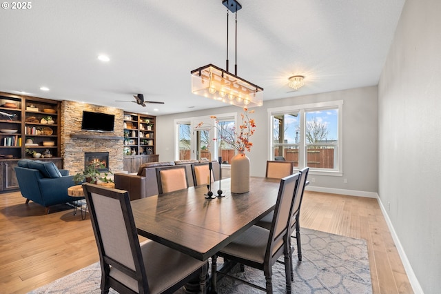 dining space with a fireplace, light hardwood / wood-style flooring, built in features, and a wealth of natural light