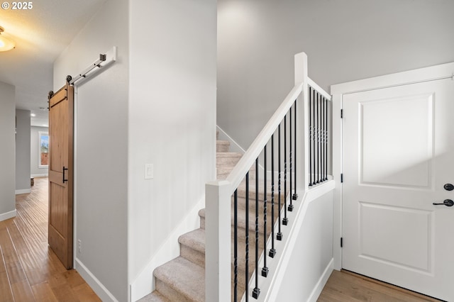 stairs with a barn door and wood-type flooring