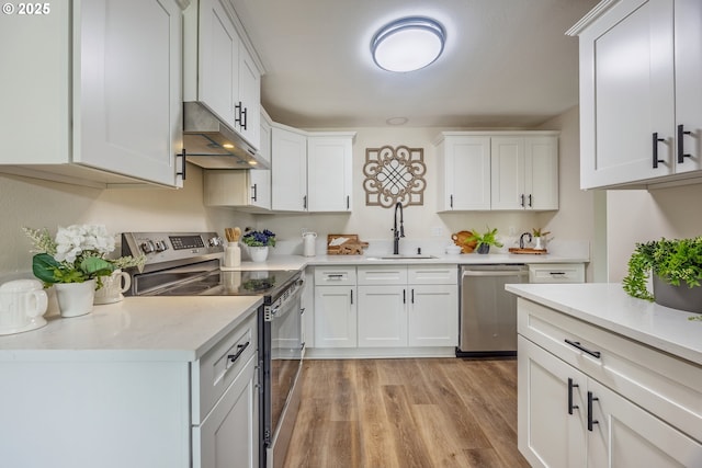 1109 SW 15th St, Lincoln City, OR 97367 - kitchen with appliances with stainless steel finishes, under cabinet range hood, white cabinets, light countertops, and light wood finished floors